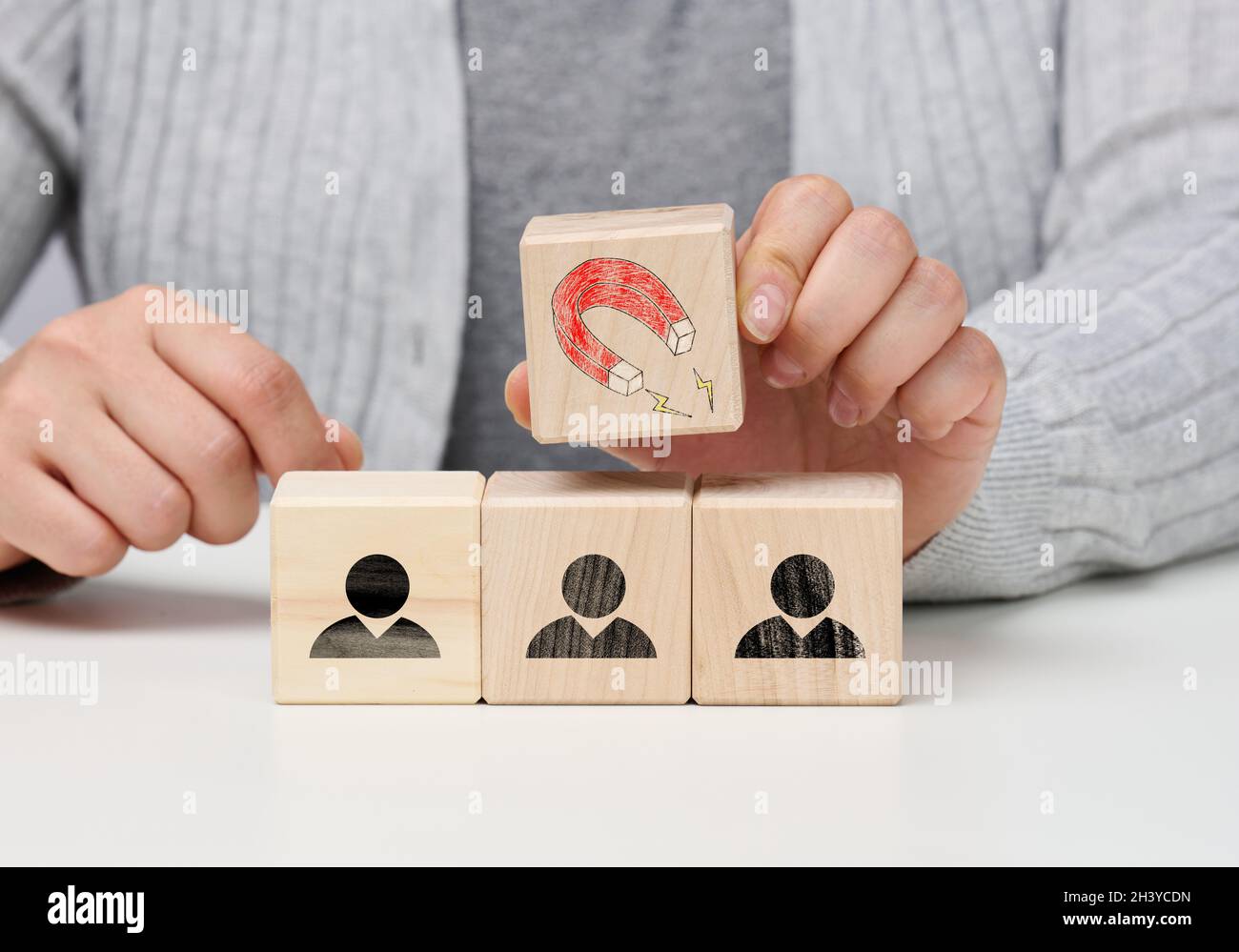 La main femelle tient un cube en bois avec un aimant sur les cubes avec des petits hommes, en recrutant pour une équipe forte.Postes vacants dans le Banque D'Images
