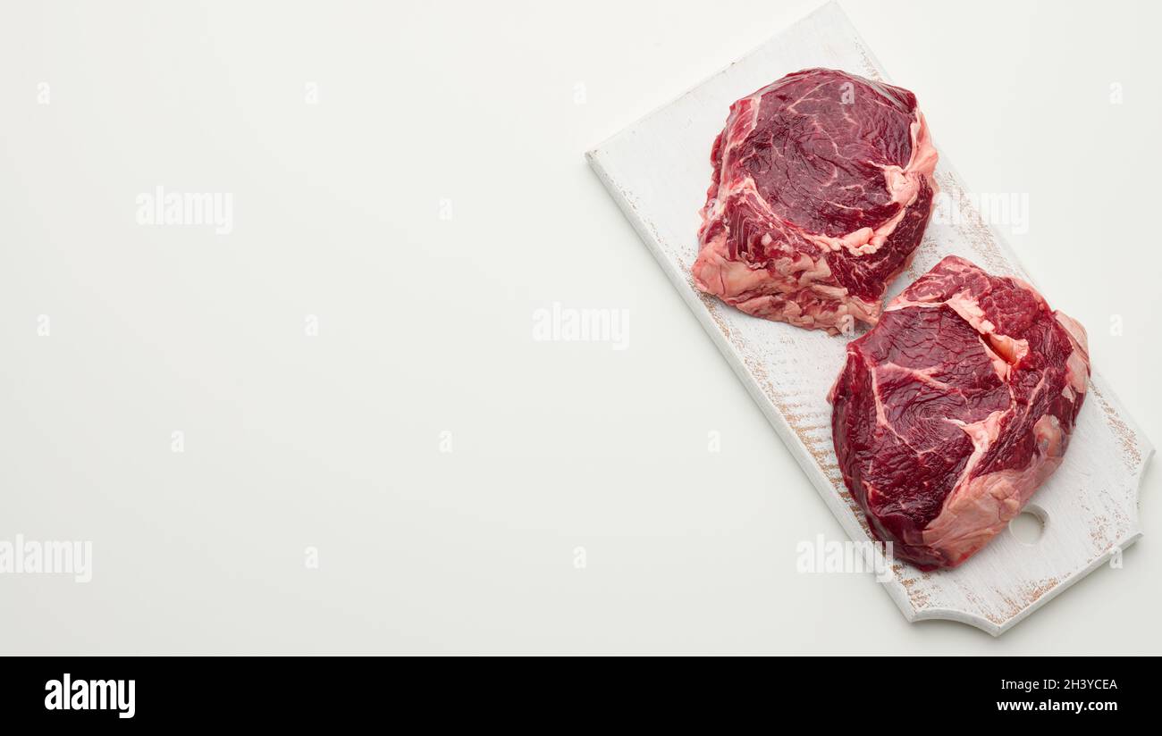 Morceau de bœuf cru à la ribeye sur fond blanc, espace de copie Banque D'Images