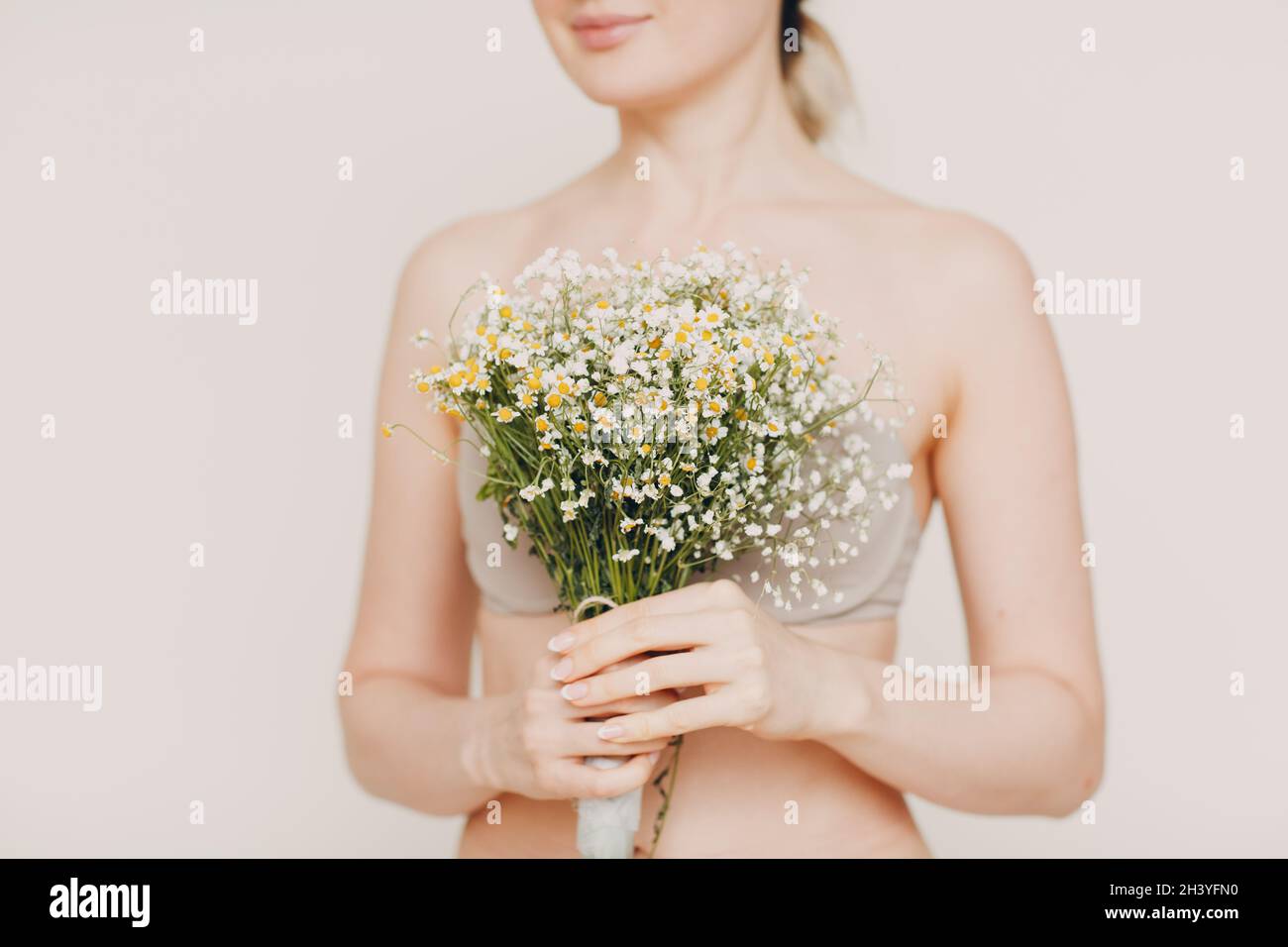 Jeune et belle femme blonde avec bouquet de camomille Banque D'Images