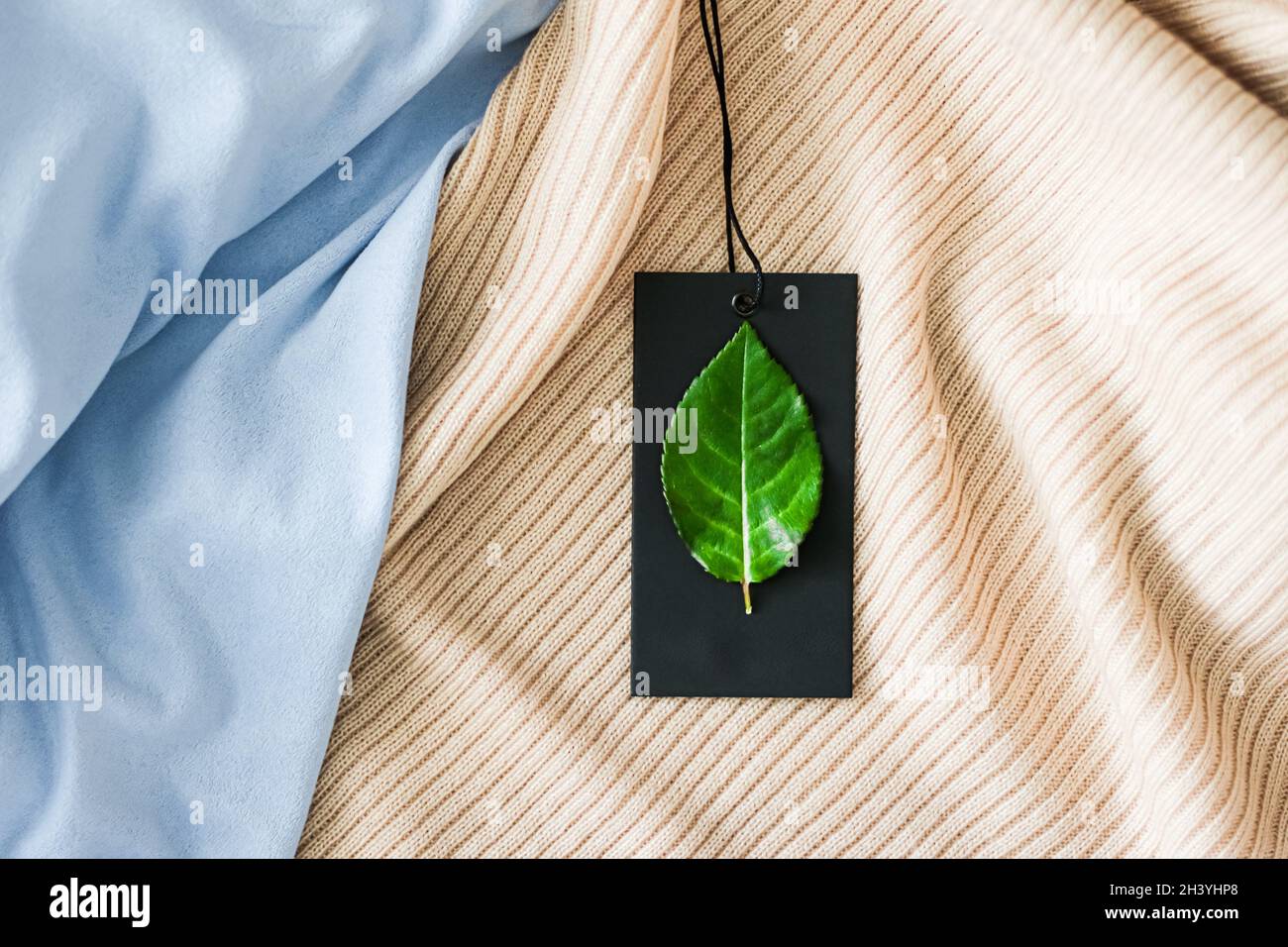 Feuille verte sur étiquette de vêtements et fond de tissu biologique, mode durable et concept de marque Banque D'Images