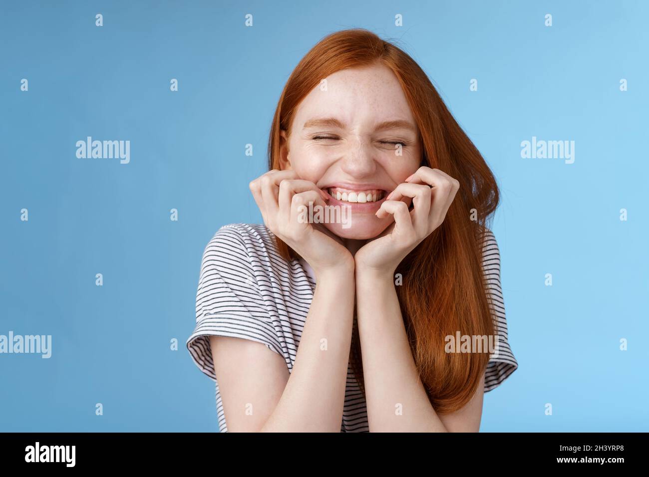 Gai insouciant Ginger gigling fille look heureux lumineux fermer les yeux souriant ravie tenir les mains joues ayant l'amusement sentiment excelle Banque D'Images