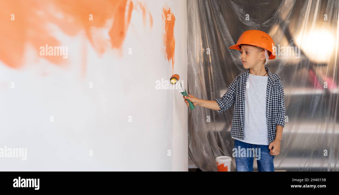 Vue Arrière Enfant Peint Un Mur Blanc Dans La Chambre. Rénovation De Maison  Ou D'appartement. Les Enfants Travaillent En Quarantaine. Un Garçon Dans Un  Casque Orange Avec De La Peinture Banque D'Images