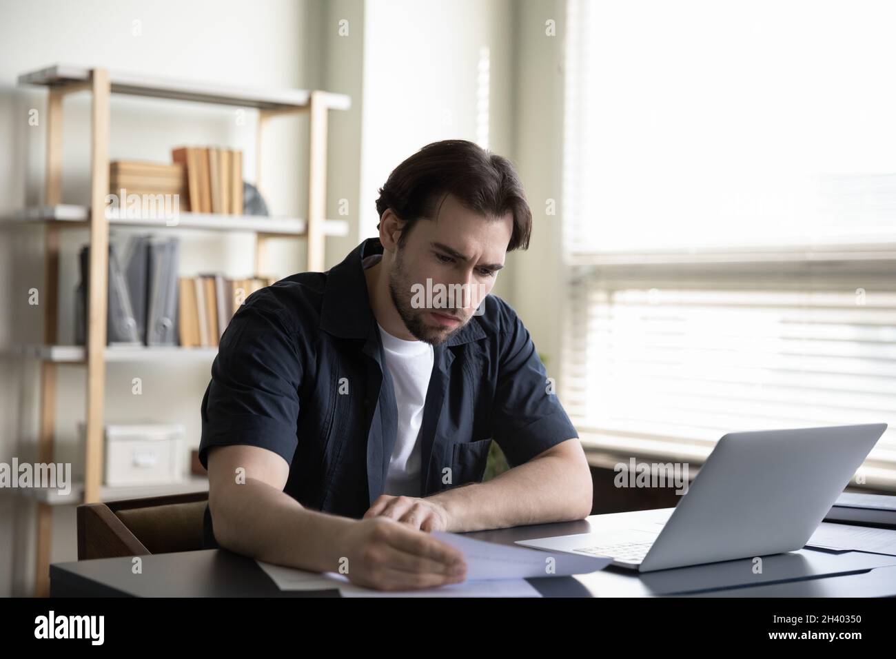 Un jeune homme d'affaires stressé examine le document papier. Banque D'Images