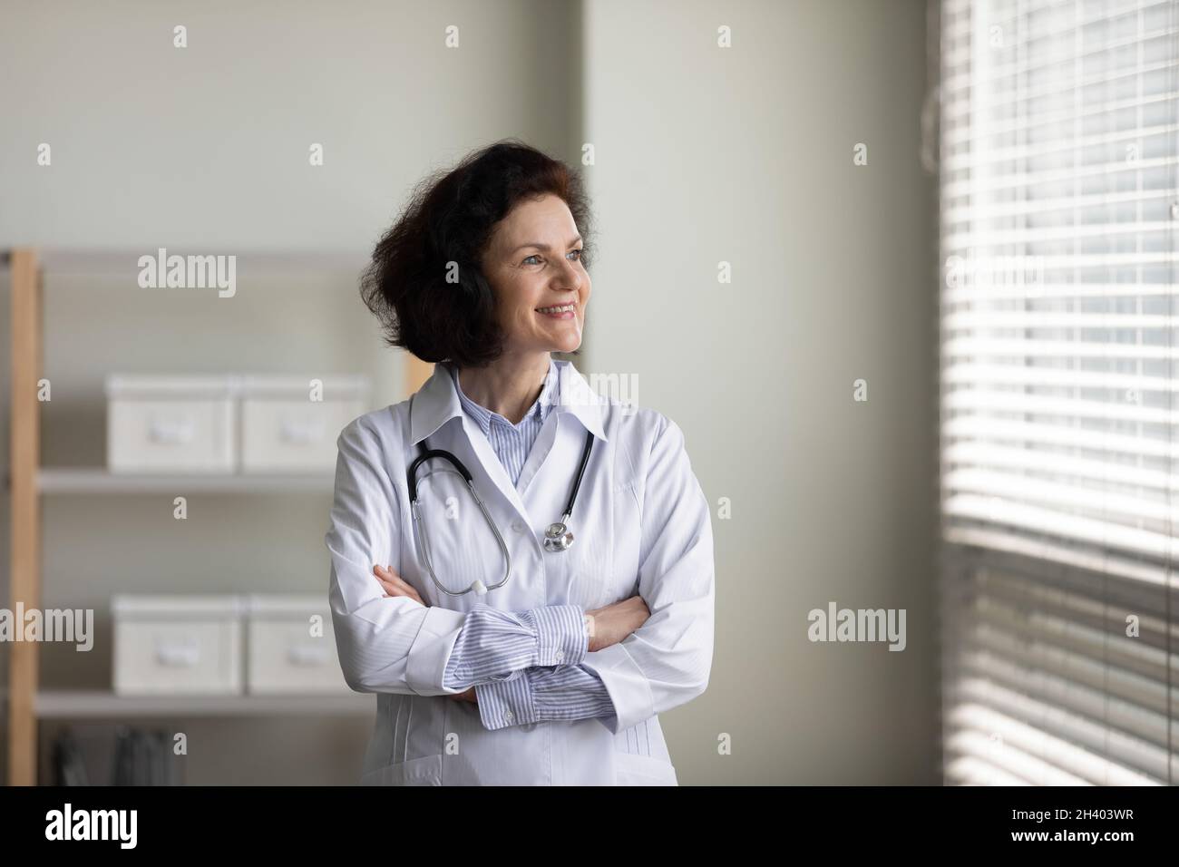 Bonne femme médecin d'âge moyen rêvant à l'intérieur. Banque D'Images