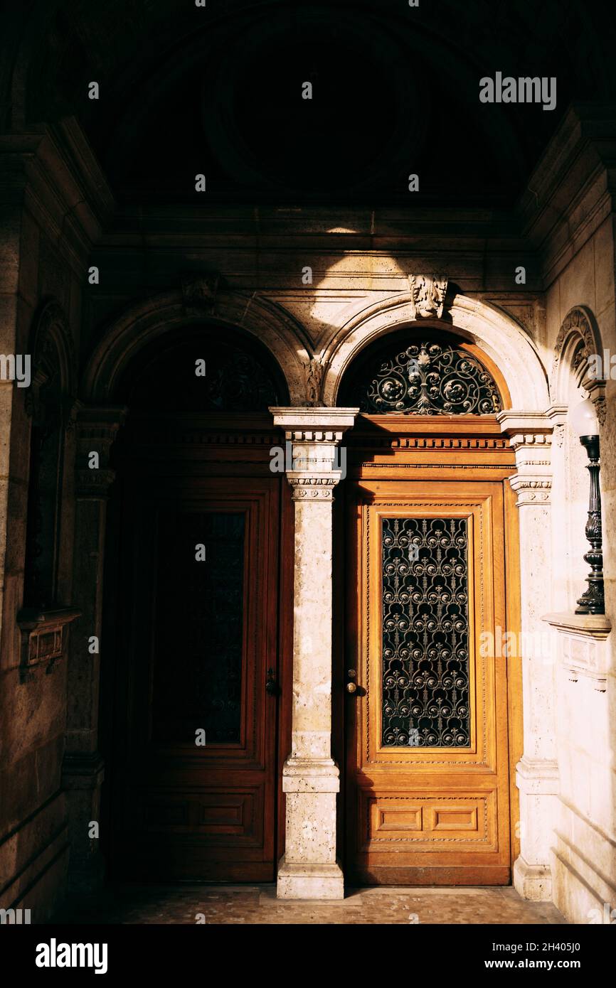 Deux portes d'entrée brunes avec de grands panneaux de verre et des barres dans les arches entre les colonnes. Banque D'Images