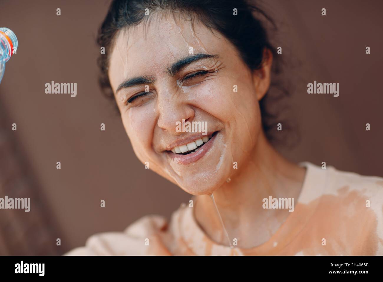 Femme stressée souffrant d'un coup de chaleur rafraîchissant avec de l'eau froide à l'extérieur.Concept de chaleur anormale par temps. Banque D'Images