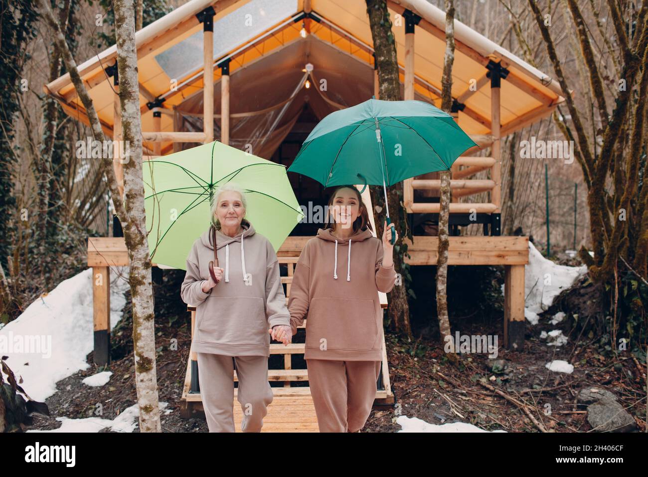 Femmes âgées et jeunes adultes avec parapluie à la tente de camping de glamping.Concept moderne de mode de vie de vacances. Banque D'Images