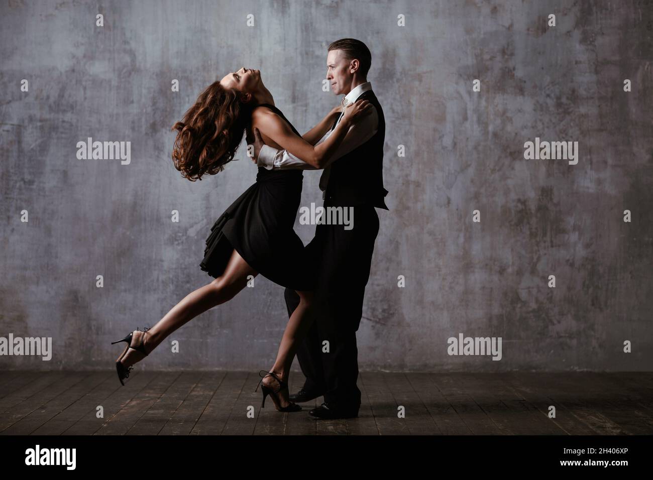 Homme et femme en robe noire danse tango en studio Banque D'Images