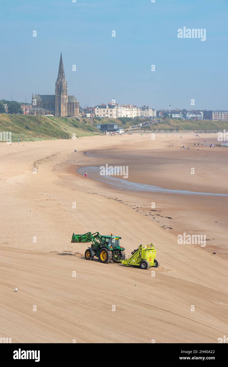 Vue sur l'église de Tynemouth et la plage et le tracteur peignant la plage Tyne & Wear Banque D'Images