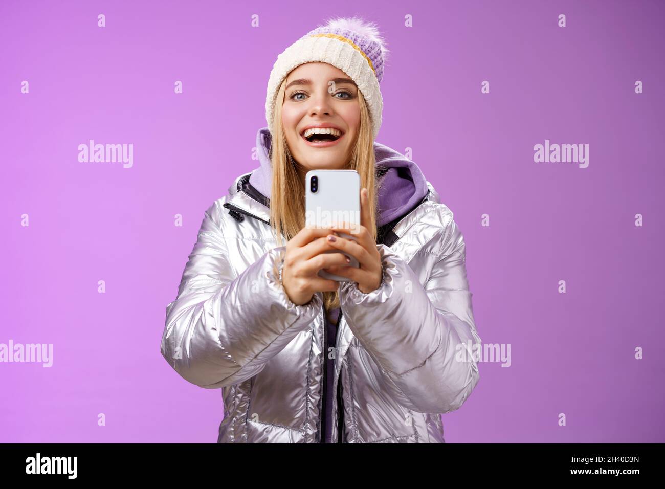 Amusant, excitée, belle petite amie blonde tenue smartphone vers le haut enregistrement vidéo petit ami étape snowboard première fois capture m Banque D'Images