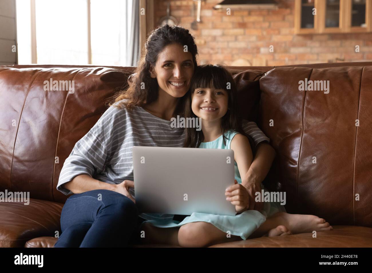 Bonne petite fille latine fille et jeune maman tenant un ordinateur portable Banque D'Images