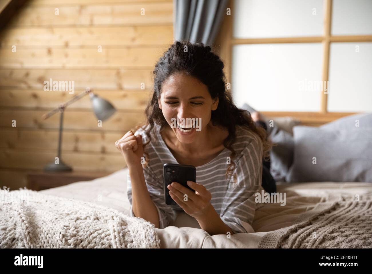 Une femme joyeuse et excitée tenant un smartphone, ce qui rend le gagnant oui à la main Banque D'Images