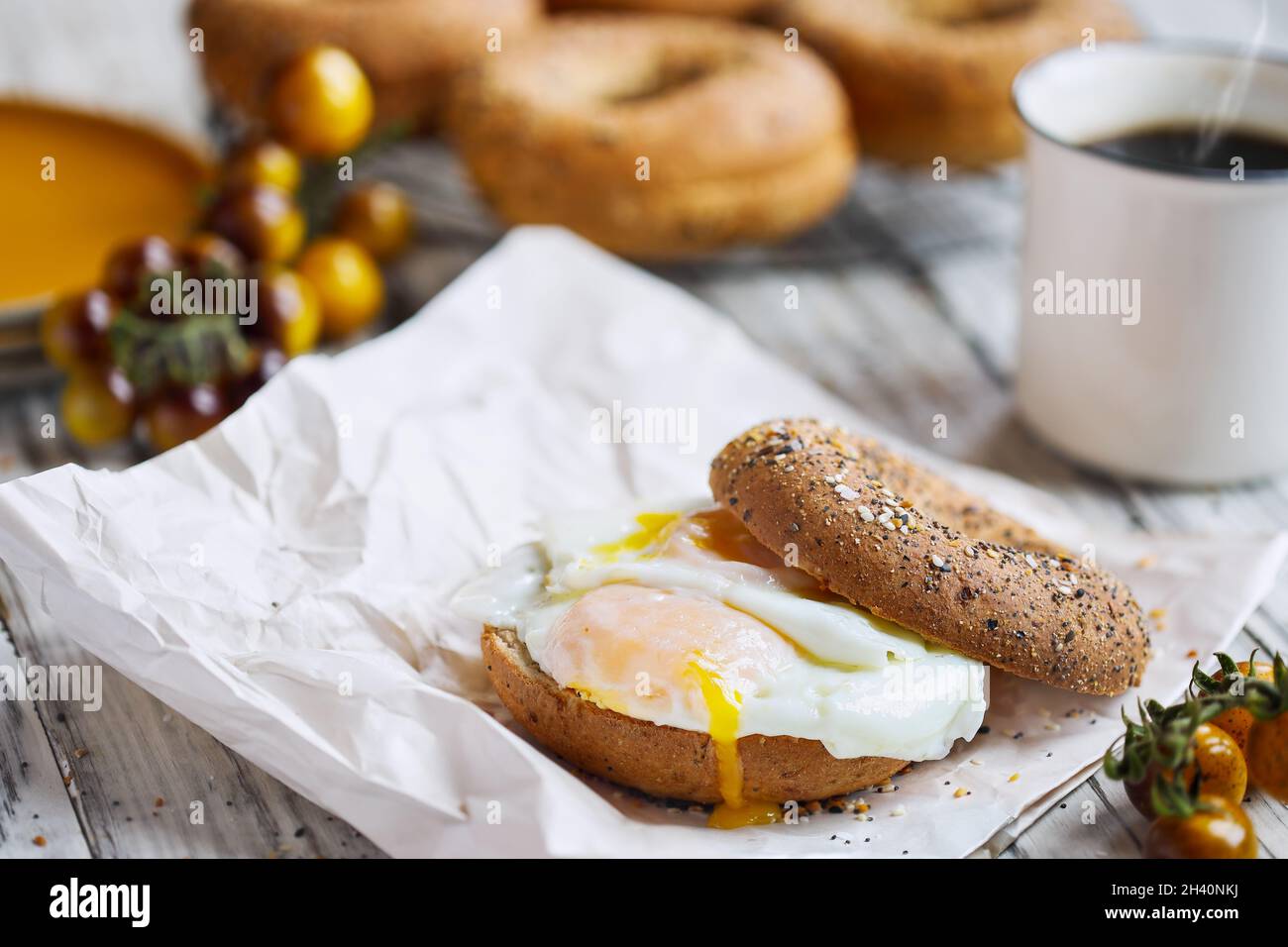 Sandwich au bagel frais et sain avec œuf frit ensoleillé, tomates cerises et café noir chaud à la vapeur.Alimentation saine.Mise au point sélective. Banque D'Images