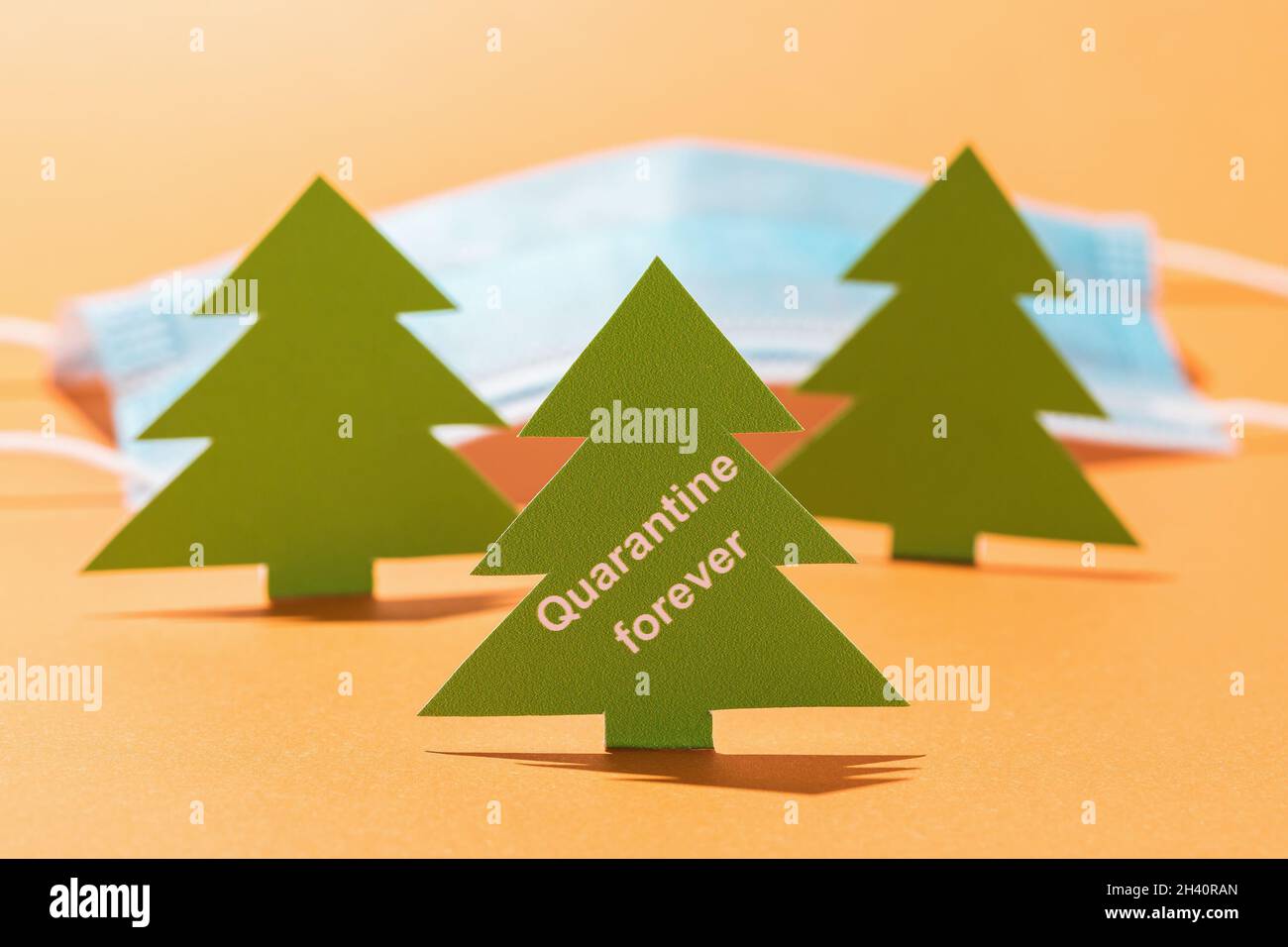 Arbre de Noël fait de carton avec du texte et un masque médical sur un fond coloré, le concept de quarantaine pour toujours Banque D'Images