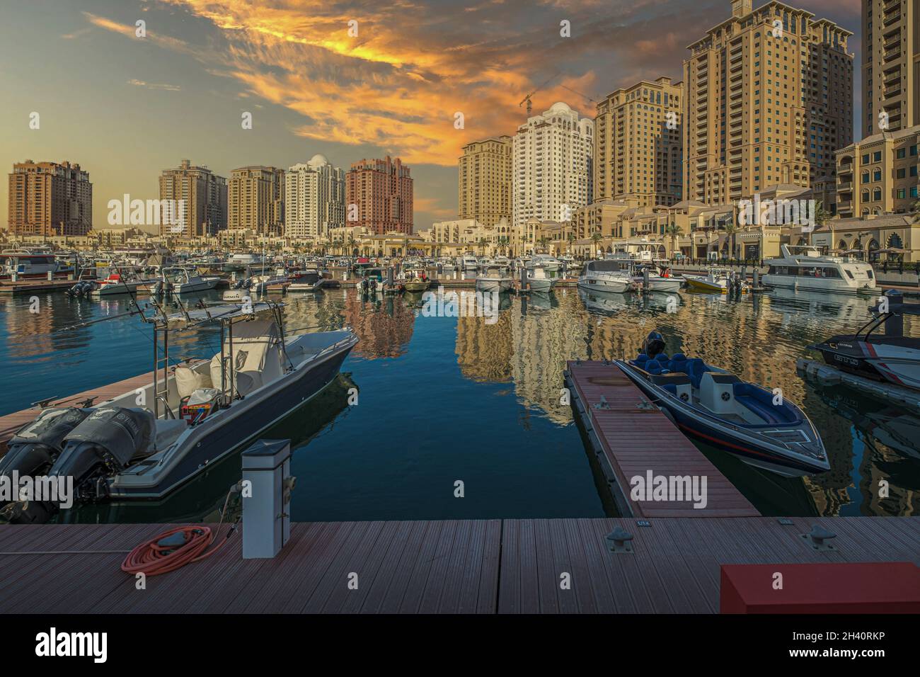 Port de plaisance de Porto Arabia dans la perle de Doha, Qatar vue au coucher du soleil montrant des yachts luxueux amarrés à la marina avec des bâtiments résidentiels en arrière-plan. Banque D'Images