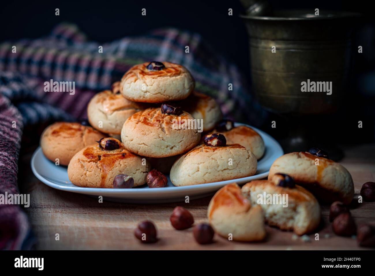 Biscuits croustillants empilés dans une assiette sur une planche de bois avec des grains de noisettes pilon et nappe Banque D'Images