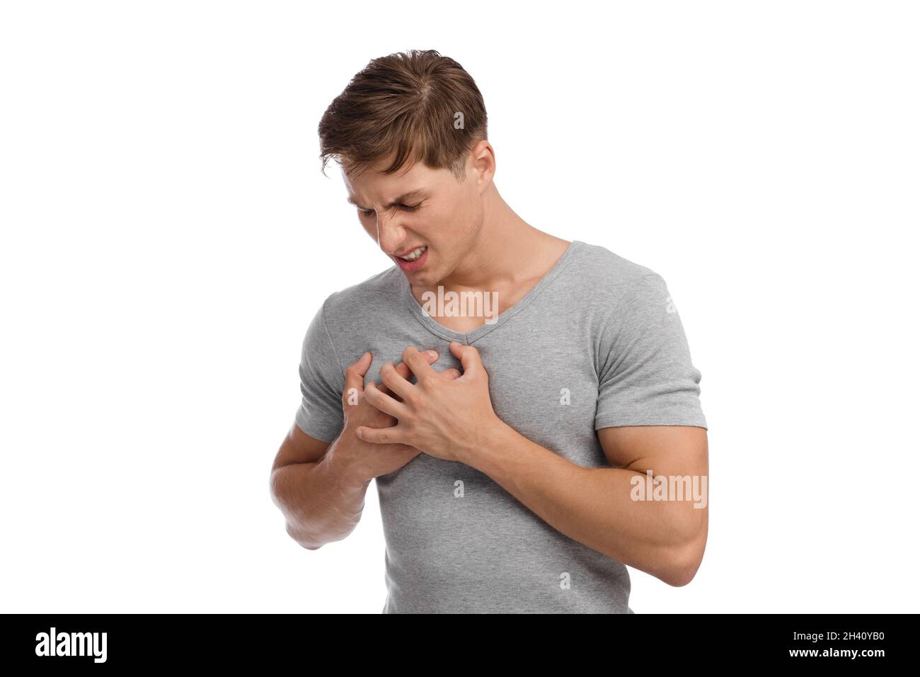 Mécontent millennal caucasien gars souffrant de douleur cardiaque et de la pression des mains à la poitrine avec l'expression douloureuse du visage Banque D'Images