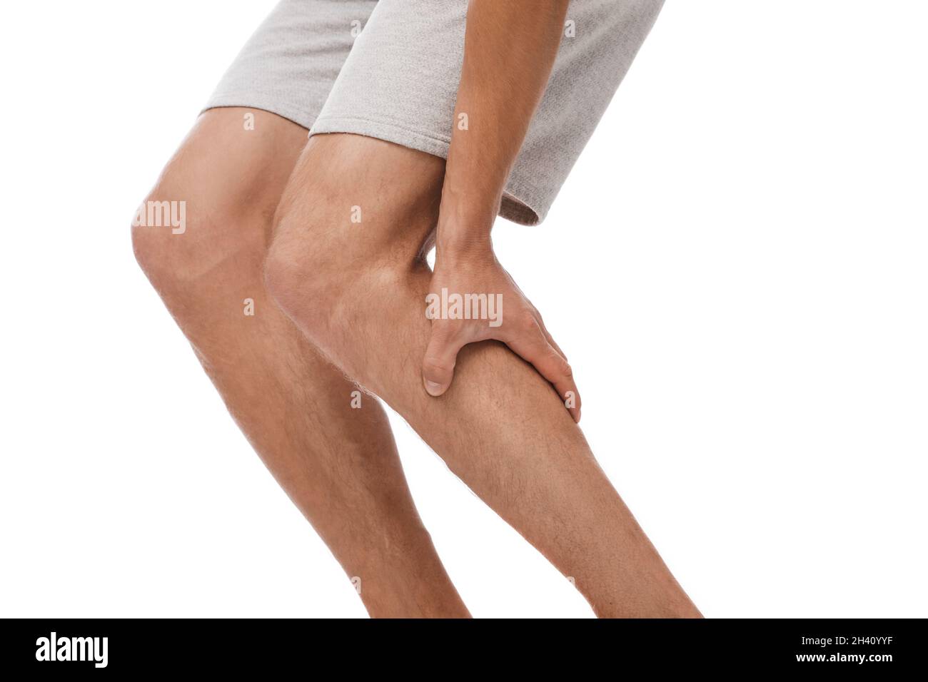 Jeune caucasien court souffrant de douleurs musculaires et se pressant des mains à la jambe Banque D'Images