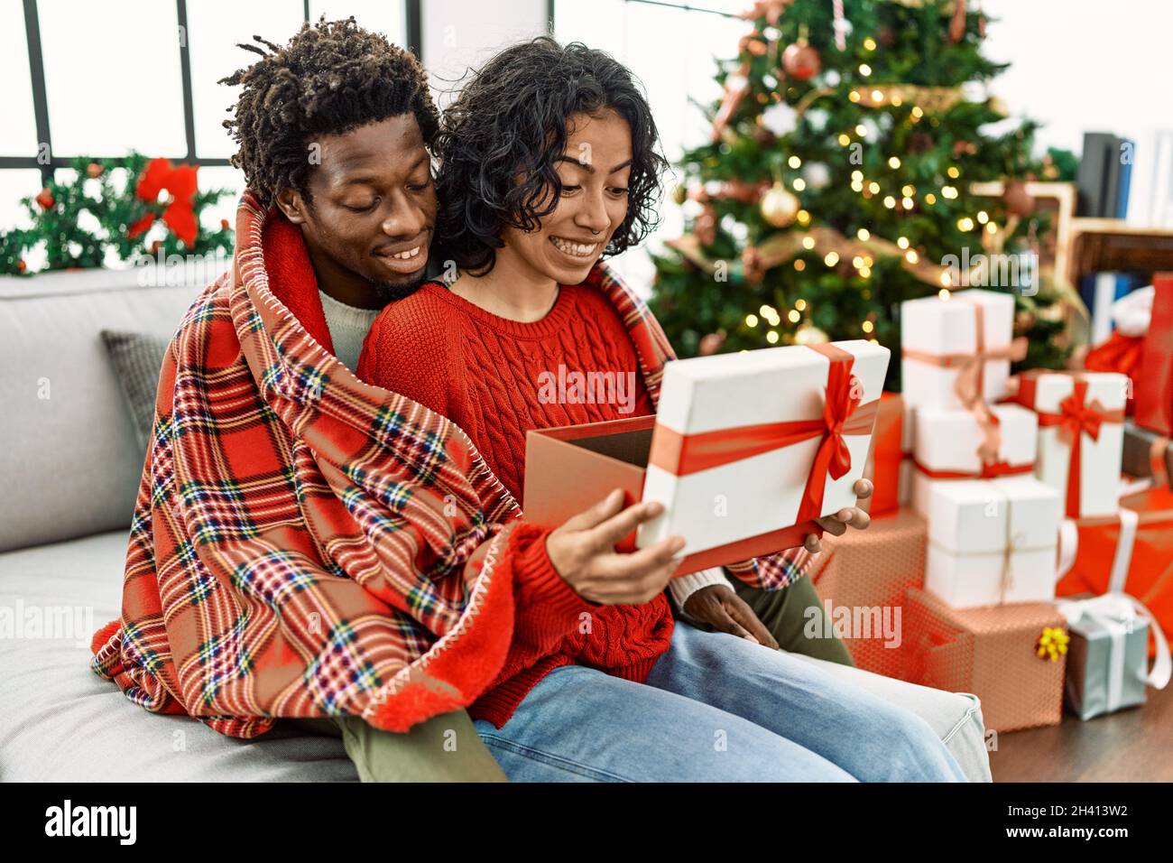 Jeune couple interracial souriant heureux cadeau de Noël unboxing assis sur  le canapé à la maison Photo Stock - Alamy
