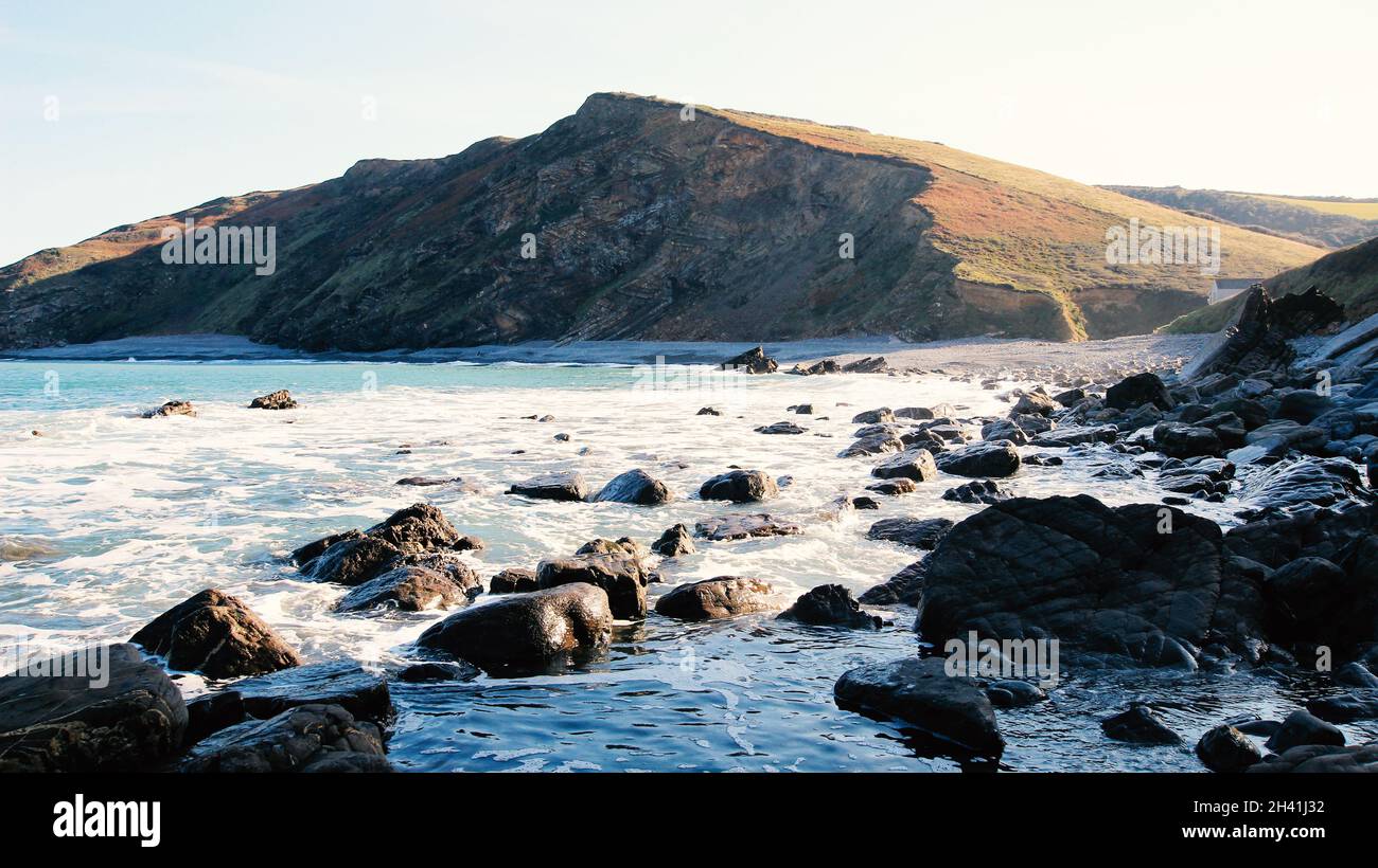 Des rochers déchiquetés et lisses le long de la côte cornish, formant une baie couverte de pierre frappée par les vagues de l'océan. Banque D'Images