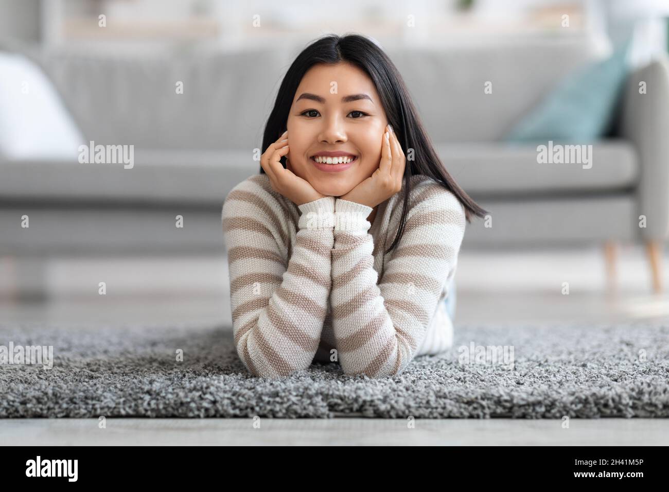 Portrait de la belle jeune femme asiatique se détendant au sol dans le salon Banque D'Images