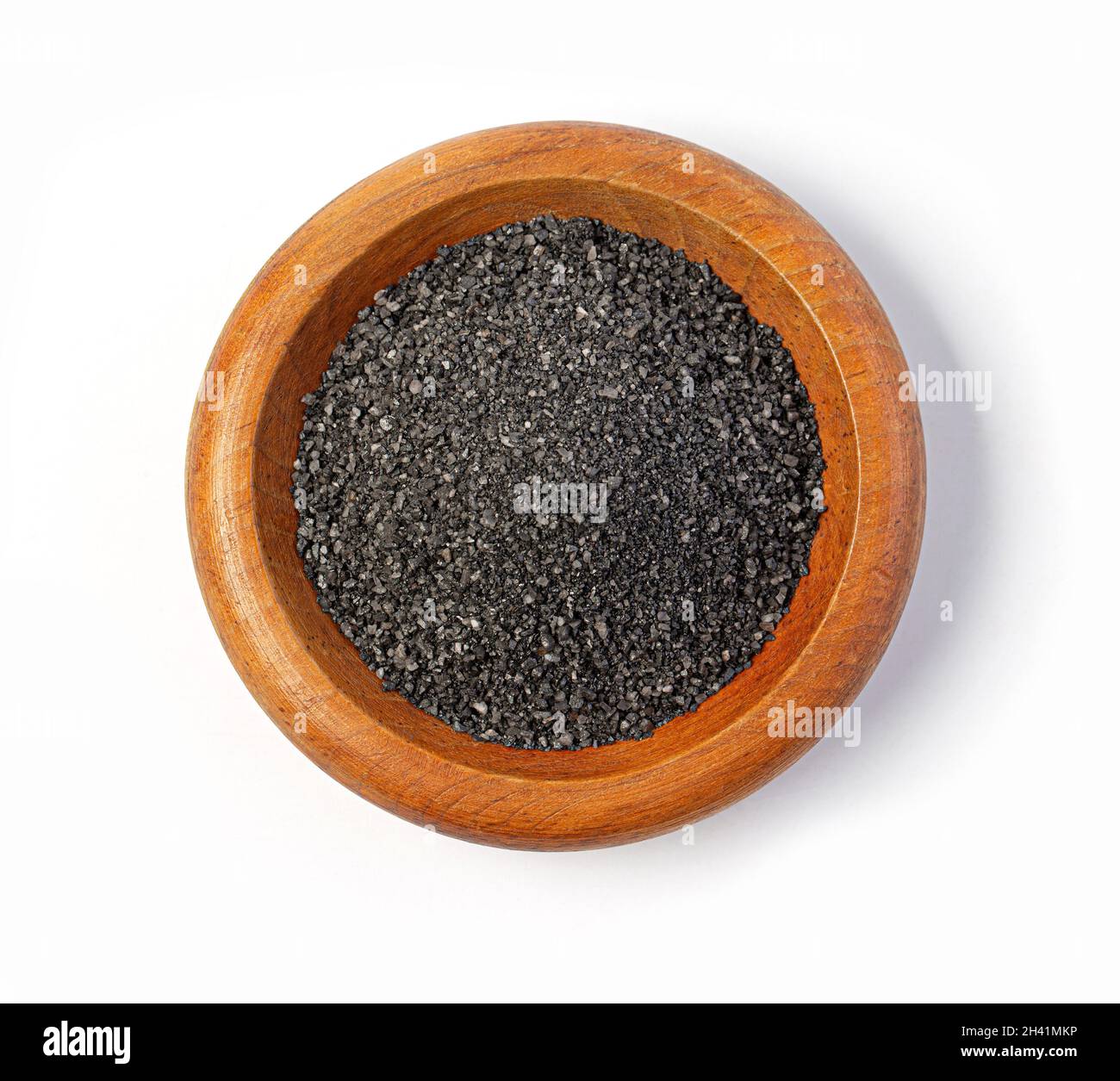 Vue de dessus du sel noir dans un bol en bois isolé blanc Banque D'Images