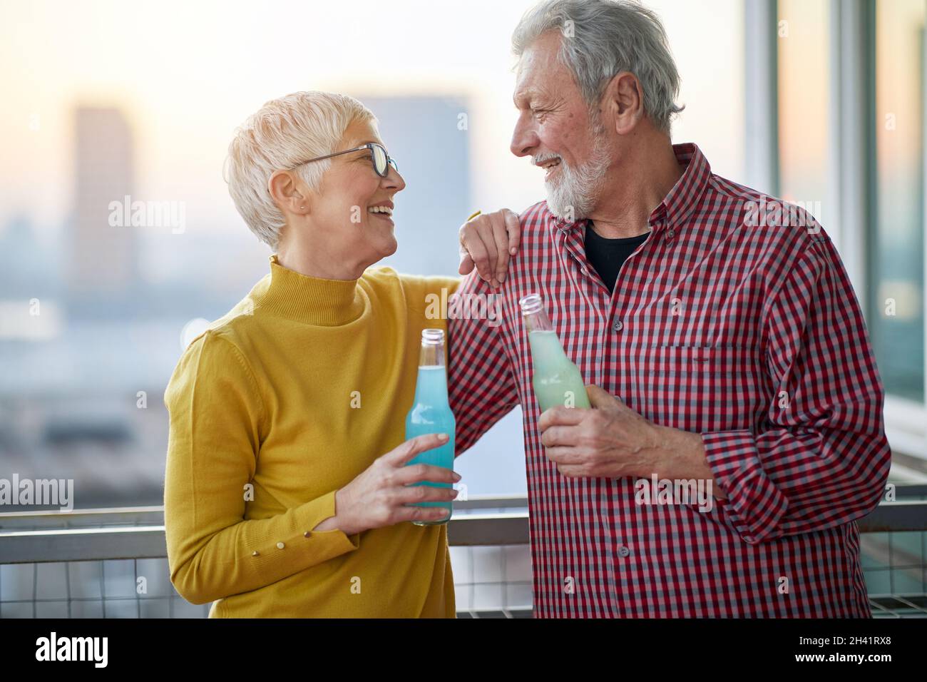 Un couple âgé embrassé en amour prend un verre dans une atmosphère détendue sur la terrasse au beau coucher de soleil sur la ville.Relation, amour, à Banque D'Images