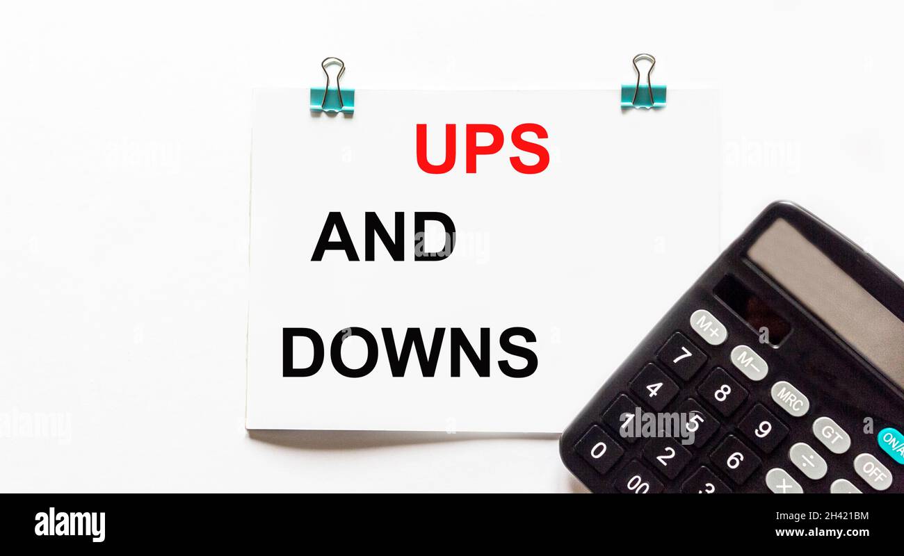 UPS et Downs, le texte est écrit sur un fond blanc, une calculatrice se trouve à proximité.Concept d'entreprise Banque D'Images