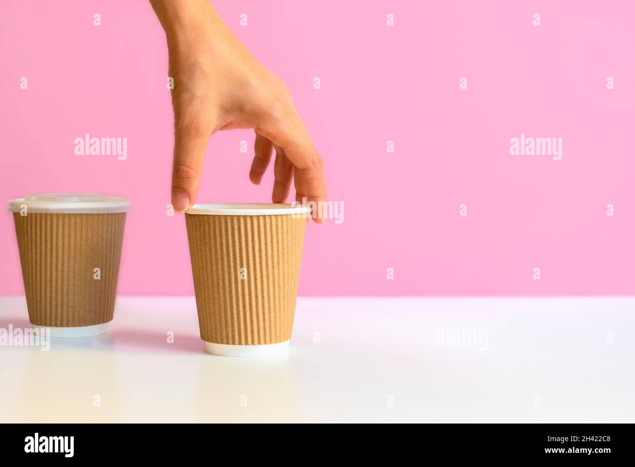 Main de femme prenant une tasse de café en papier de table blanche.Image avec espace de copie, concept zéro gaspillage Banque D'Images