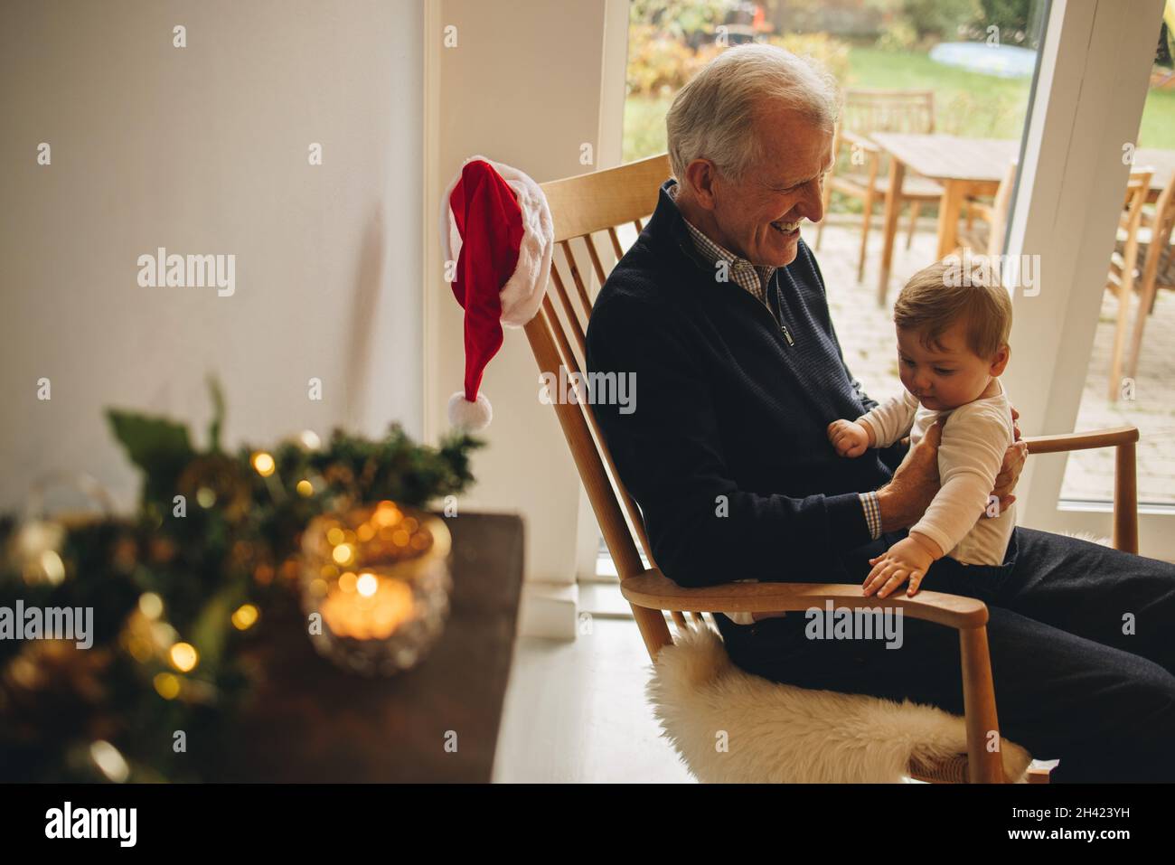 Homme senior assis sur une chaise et avec son petit-fils.Grand-père et petit-fils ensemble à noël. Banque D'Images