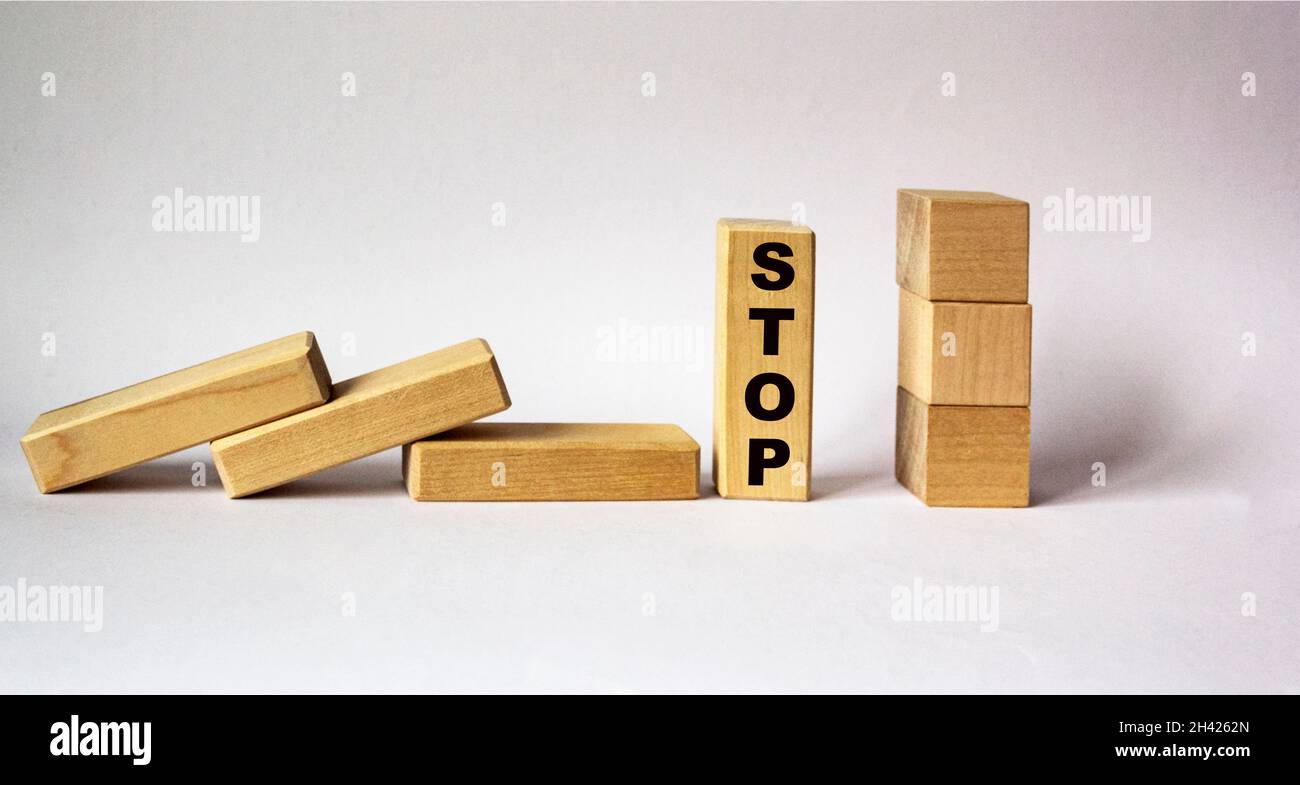 Concept de la butée à main tombant des blocs de bois sur un fond blanc.Sur le bloc, le mot STOP. Banque D'Images