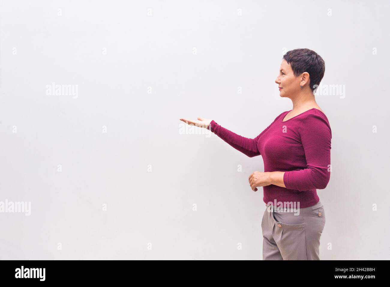femme pointant vers le côté droit avec l'espace de copie, contre un mur blanc Banque D'Images