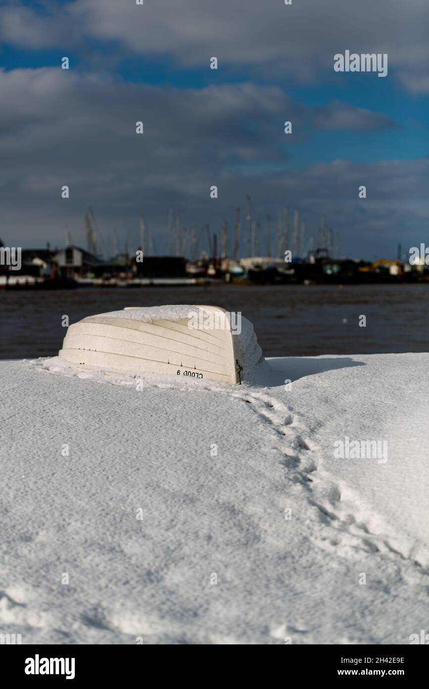 Des bateaux à rames ont été laissés amarrés sur la plage sur la côte du Suffolk.Ils ont été couverts de neige après une rare tempête de neige qui couvre la région Banque D'Images