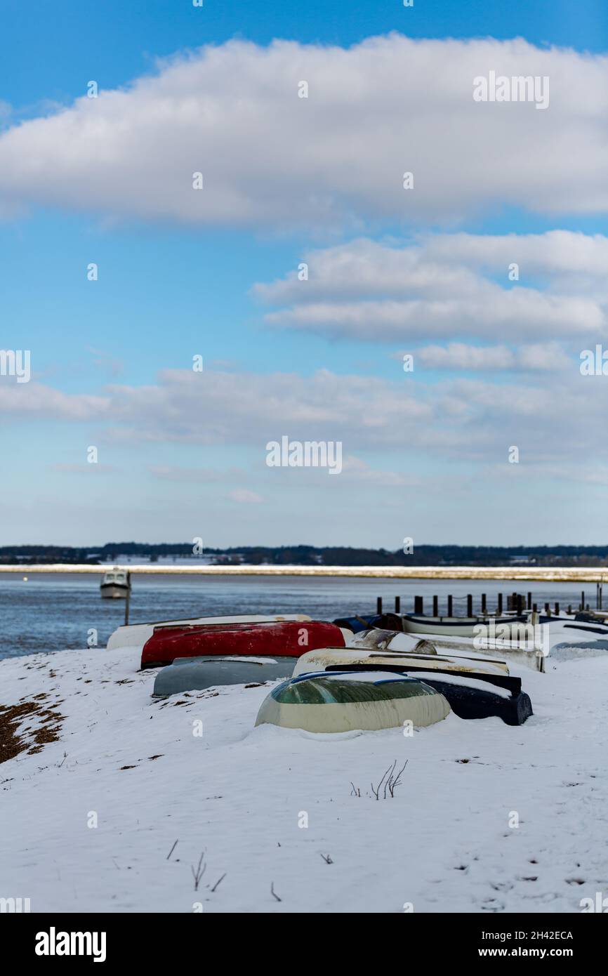 Des bateaux à rames ont été laissés amarrés sur la plage sur la côte du Suffolk.Ils ont été couverts de neige après une rare tempête de neige qui couvre la région Banque D'Images