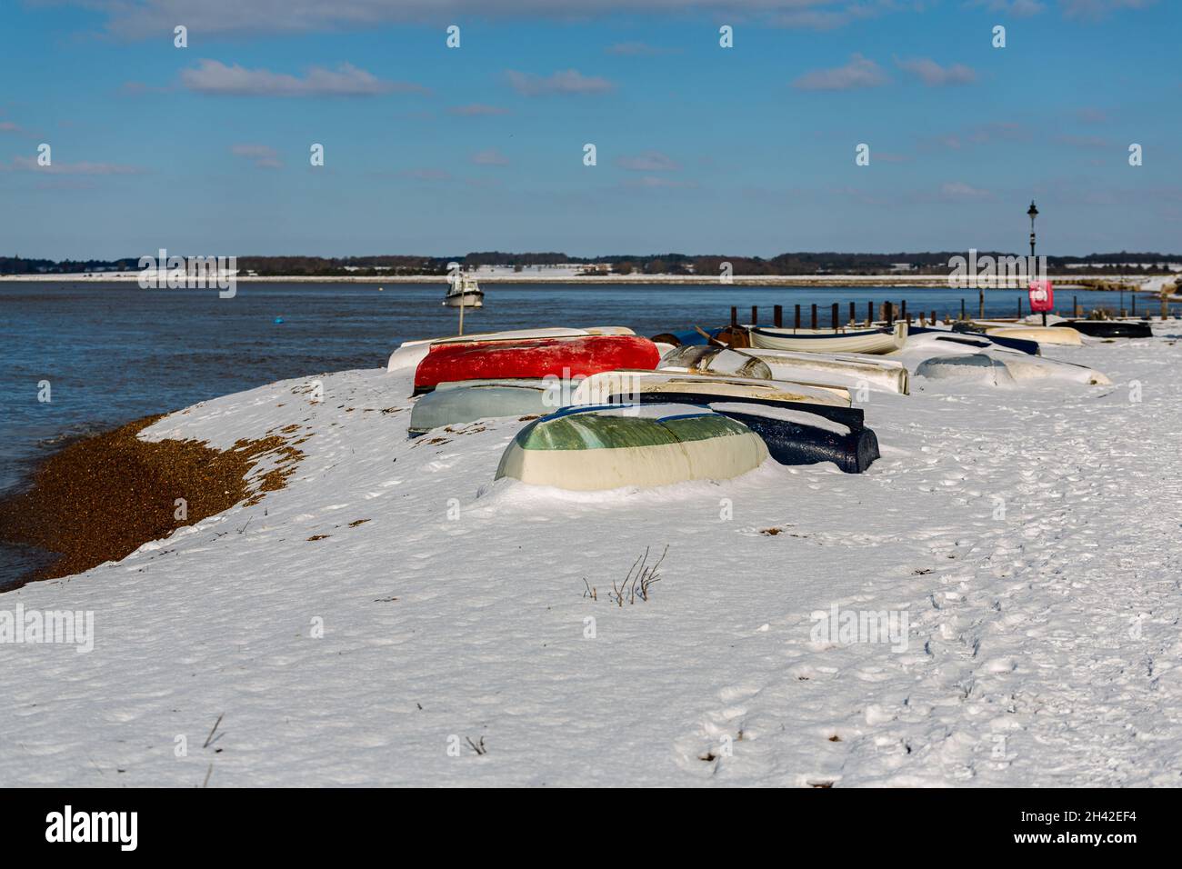 Des bateaux à rames ont été laissés amarrés sur la plage sur la côte du Suffolk.Ils ont été couverts de neige après une rare tempête de neige qui couvre la région Banque D'Images