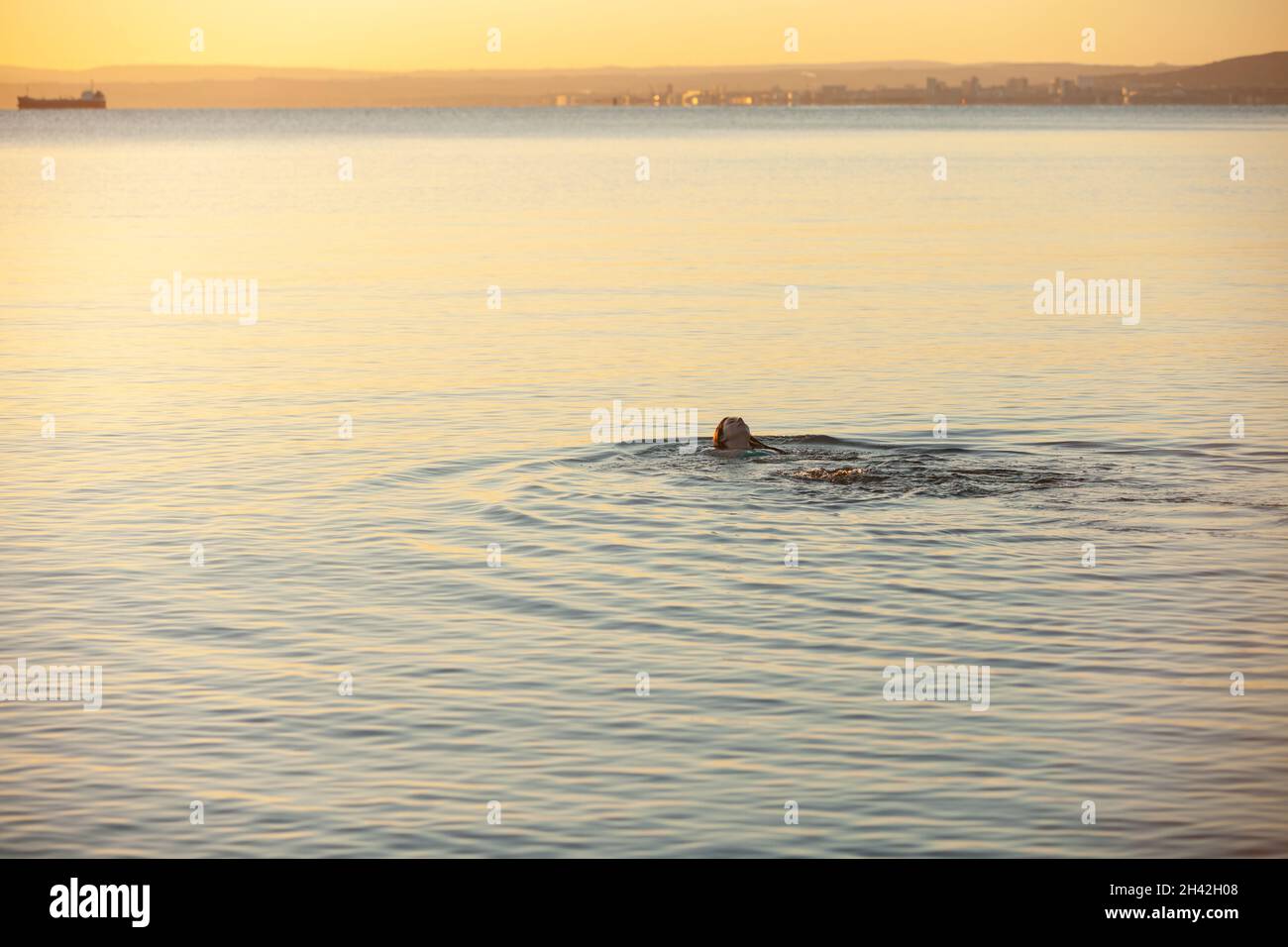 Une jeune écossaise nageant d'eau froide au lever du soleil dans la mer à Aberdour en octobre, à Fife, en Écosse Banque D'Images