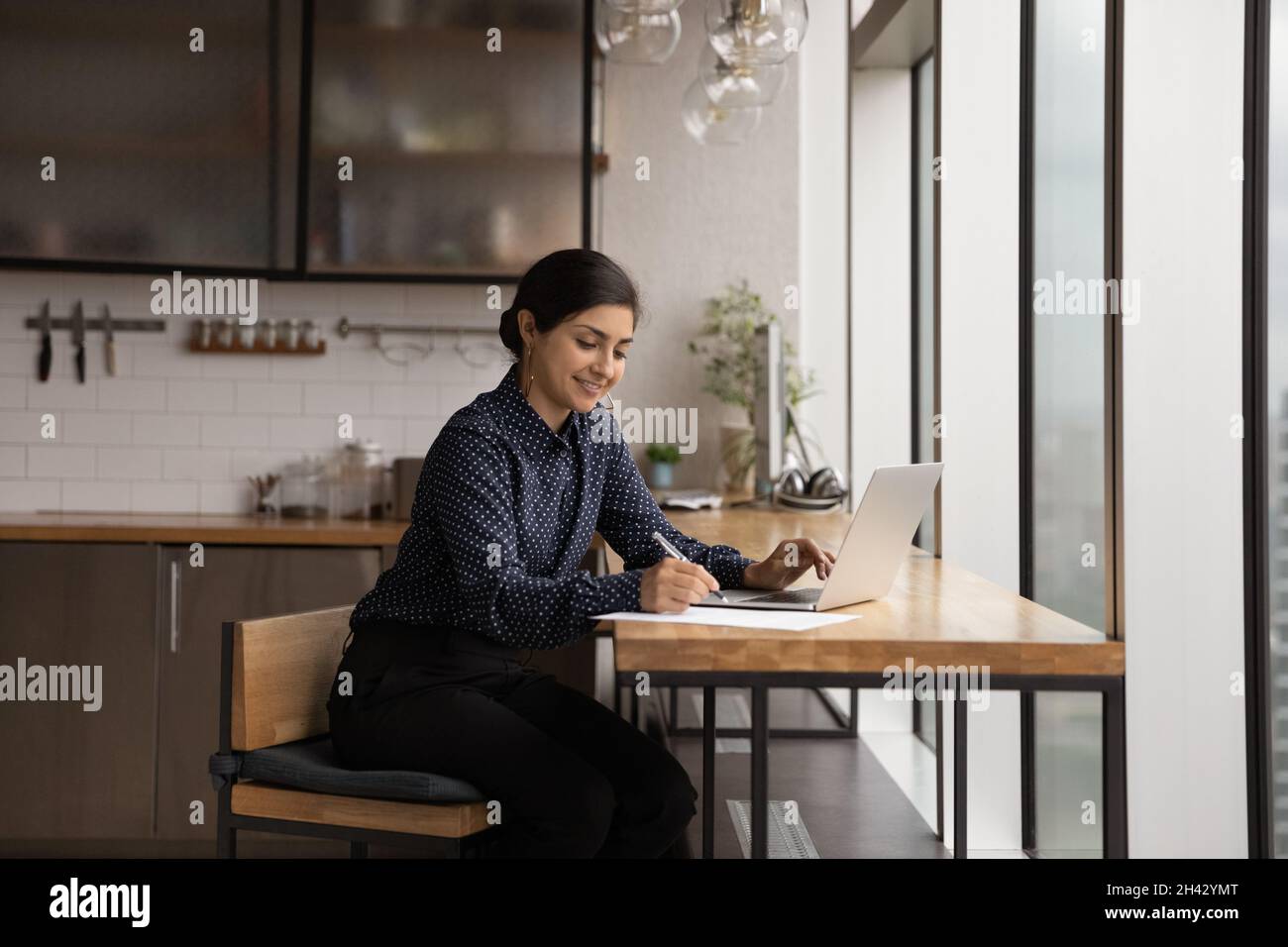 Jeune femme indienne souriante écrivant des notes, étudiant à la maison. Banque D'Images