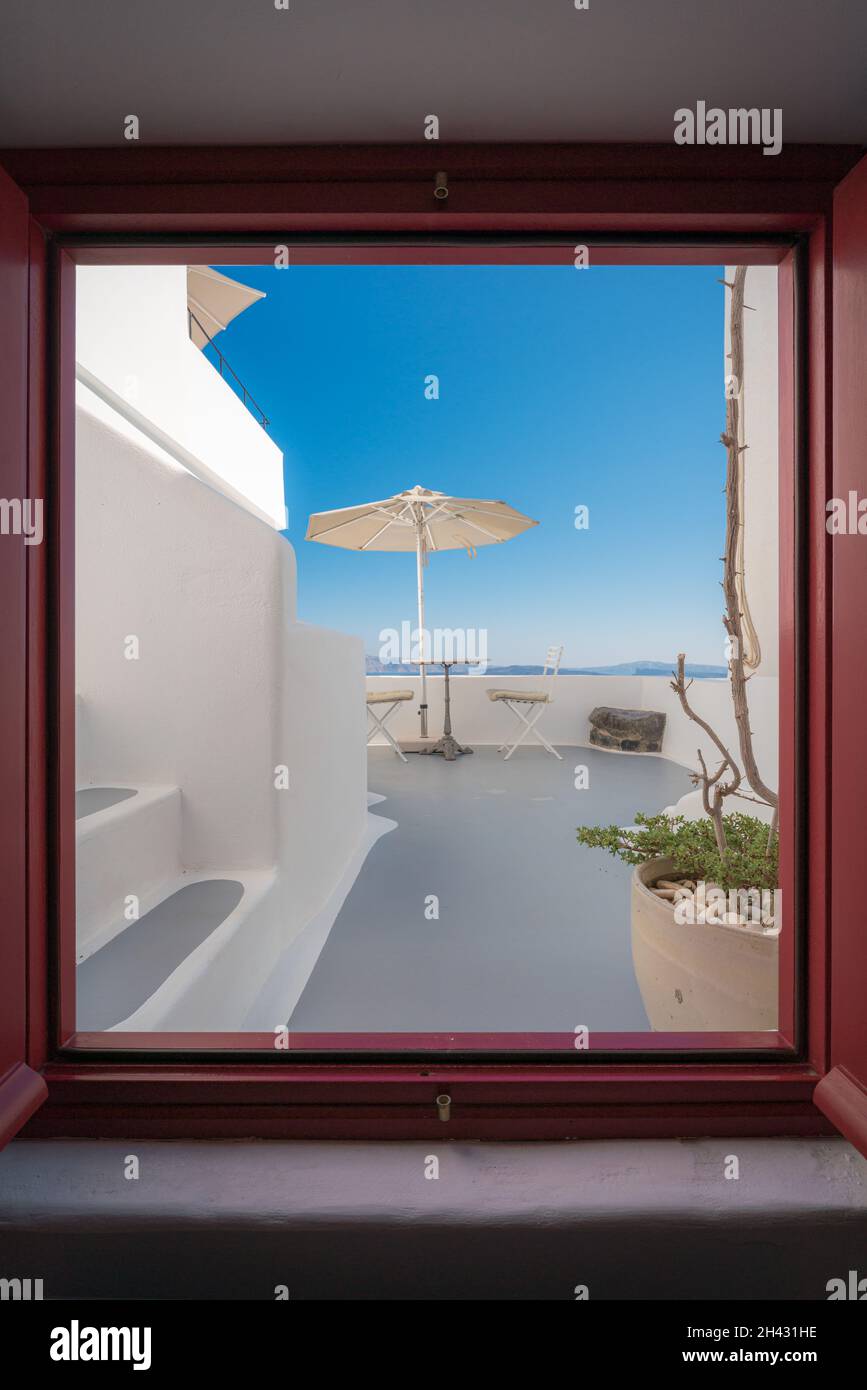 Vue sur la terrasse avec parasol, bureau et chaises depuis une fenêtre Banque D'Images