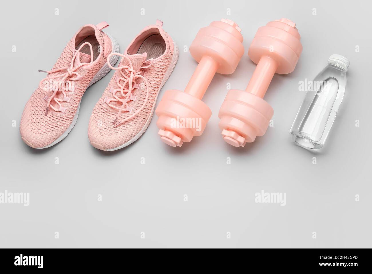 Haltères, chaussures et bouteille d'eau sur fond clair Banque D'Images