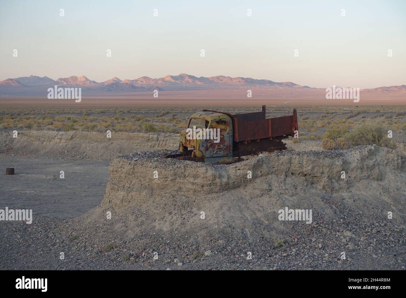 Au cœur du désert du Nevada, une sentinelle rouillée se dresse au sommet de son trône sablonneux - un châssis de camion oublié, embrassé par le temps et le soleil Banque D'Images