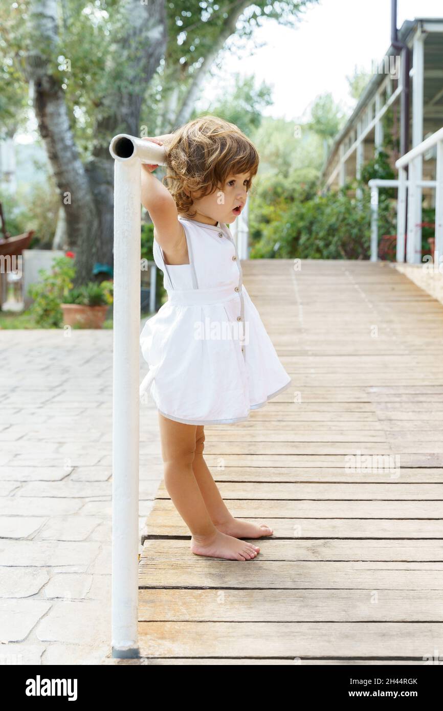 Adorable petite fille en robe blanche jouant Banque D'Images