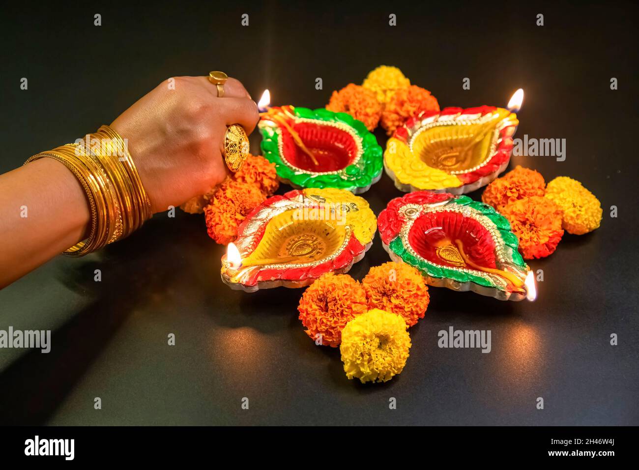 Femme éclairage à la main lampes traditionnelles en argile Diya avec décoration florale pour un fond festif. Banque D'Images
