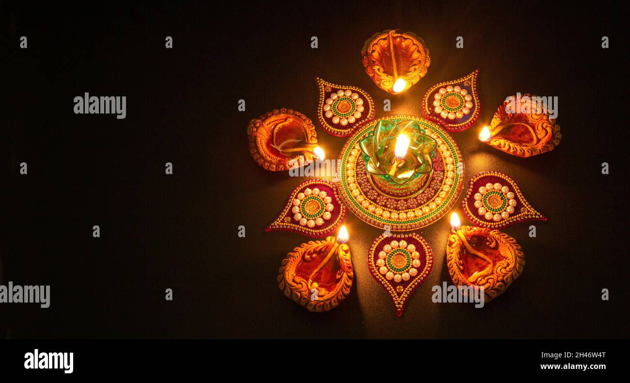 Les lampes Diya en argile traditionnelle de Diwali sont illuminées dans un fond sombre avec des rangoli Banque D'Images