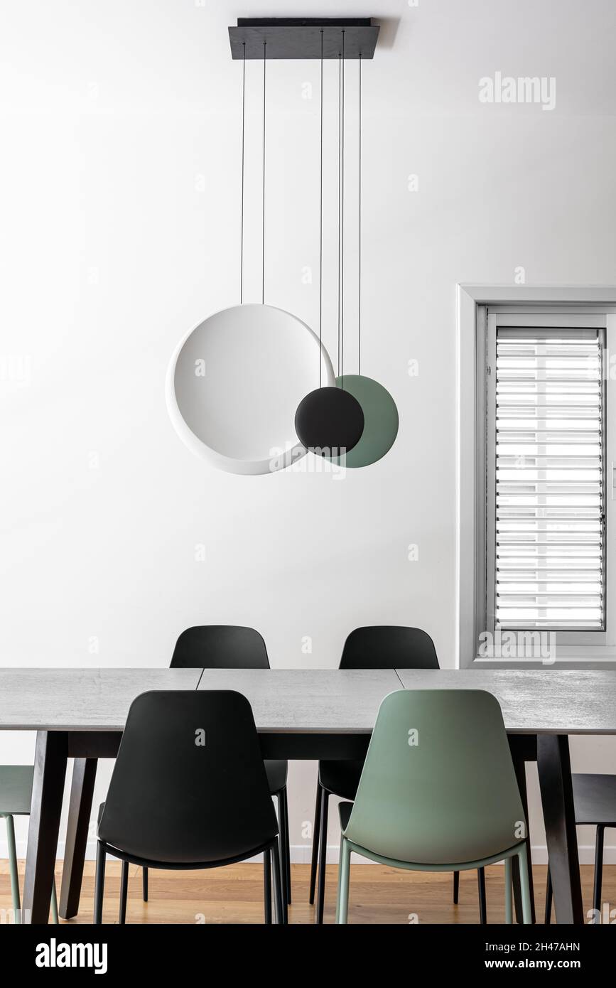 Coin repas dans l'appartement avec table et chaises et luminaire suspendu au plafond, vert olive, noir et blanc Banque D'Images