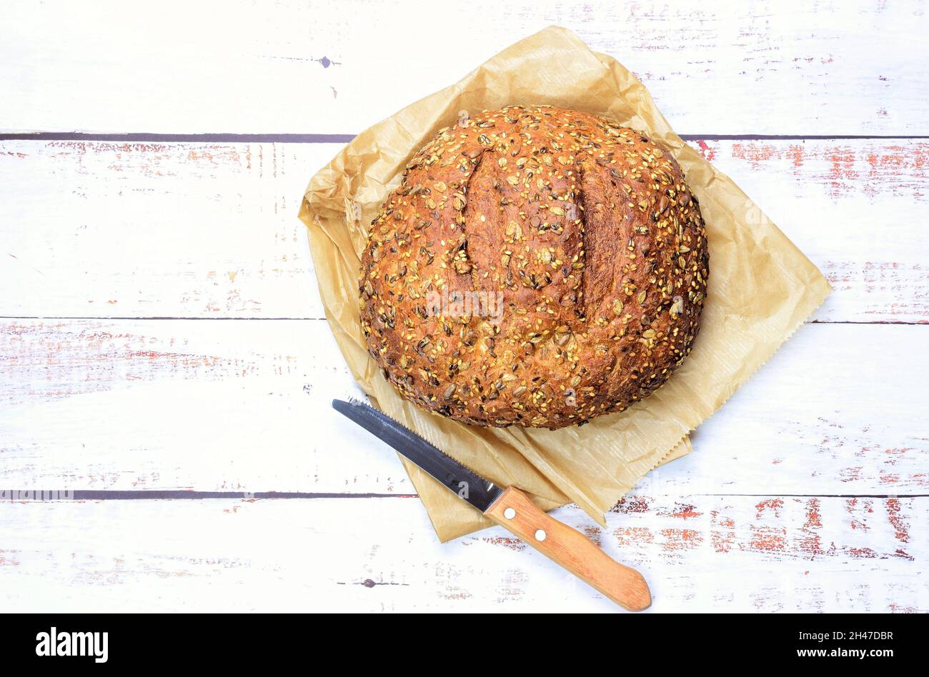 Vue de dessus de pain de seigle sur une serviette sur un fond rustique en bois avec un couteau Banque D'Images