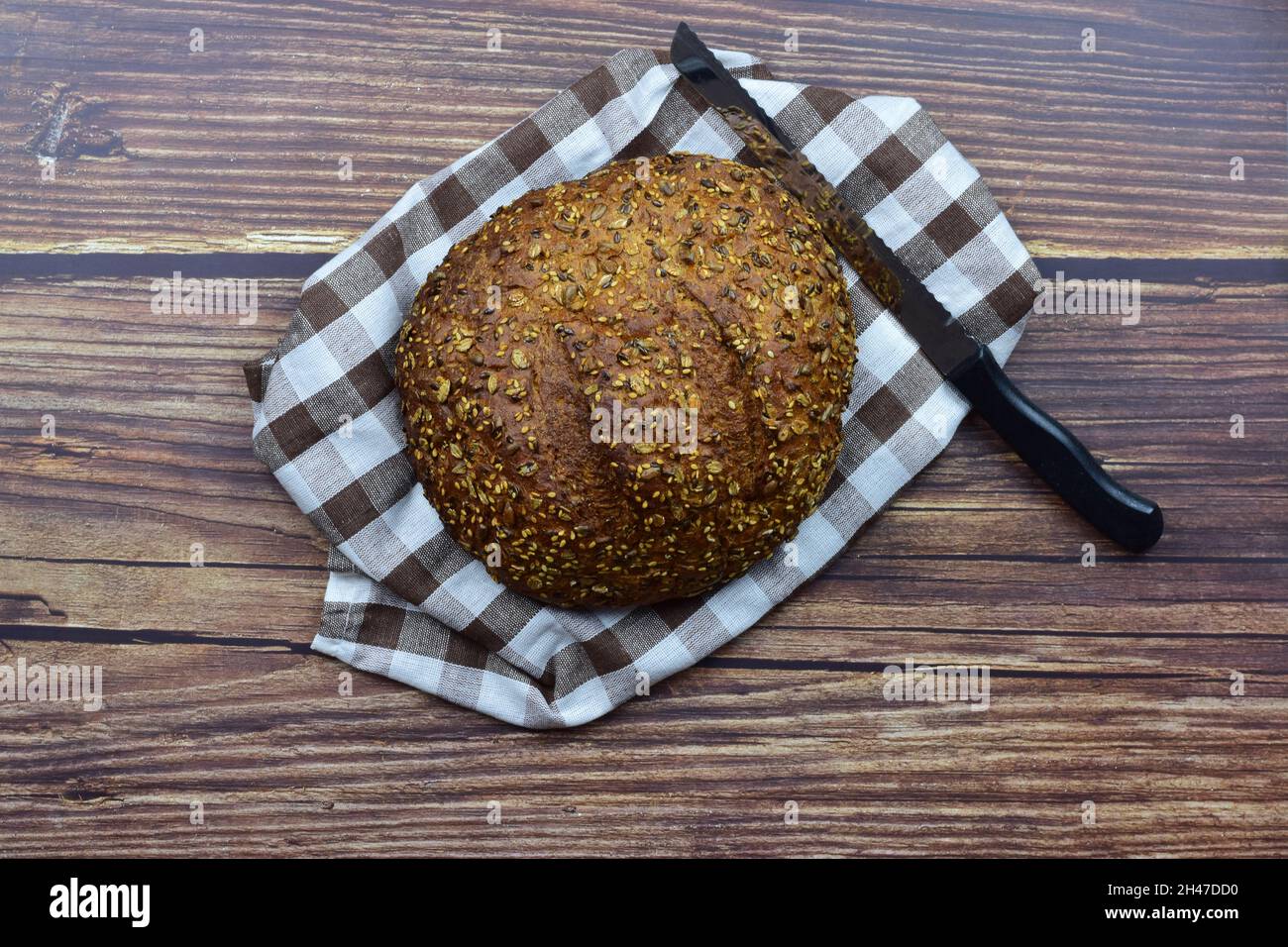 Vue de dessus photo d'un couteau et du pain de seigle sur une tour à carreaux sur un fond de bois rustique Banque D'Images