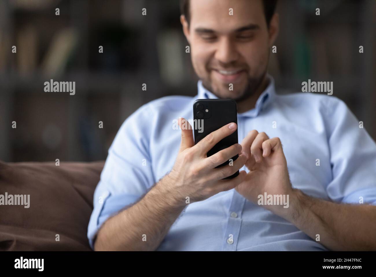 Jeune homme joyeux utilisant des applications de téléphonie cellulaire à la maison. Banque D'Images