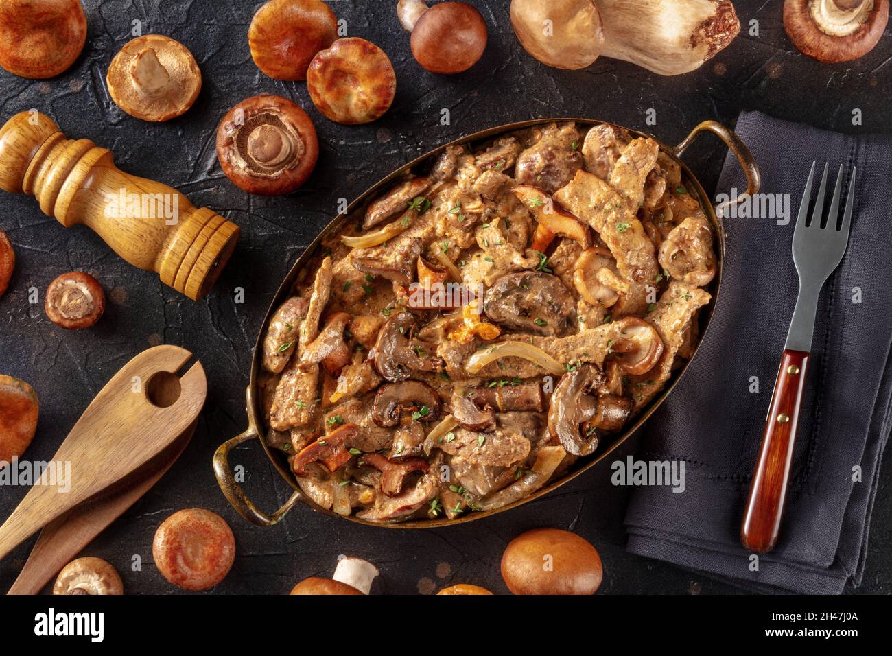Ragoût de bœuf, de champignons et de viande avec sauce crème, dans une casserole avec ingrédients, plan de travail à plat sur fond d'ardoise noire Banque D'Images
