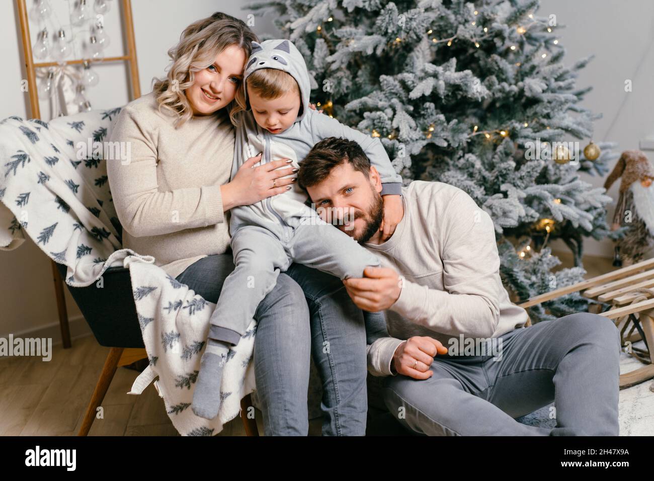 Bonheur de la famille de Noël Portrait de papa, mère enceinte et petit fils assis fauteuil à la maison près de l'arbre de Noël hug sourire européen jeune adulte f Banque D'Images