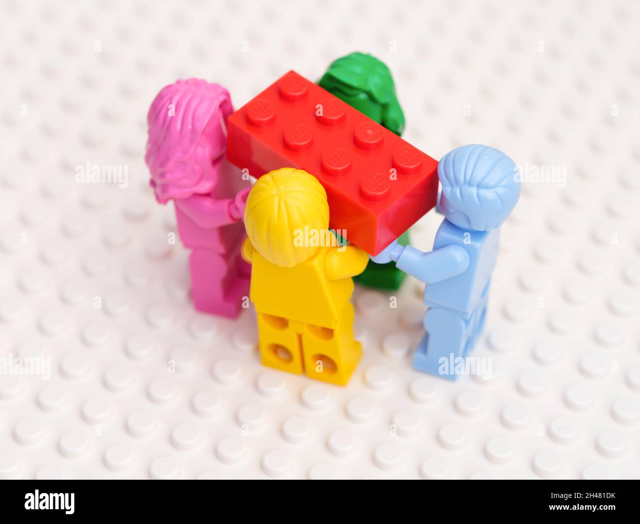 Tambov, Fédération de Russie - 17 octobre 2021 quatre figurines Lego monochromes portant une brique Lego rouge.Arrière-plan blanc.Prise de vue en studio. Banque D'Images